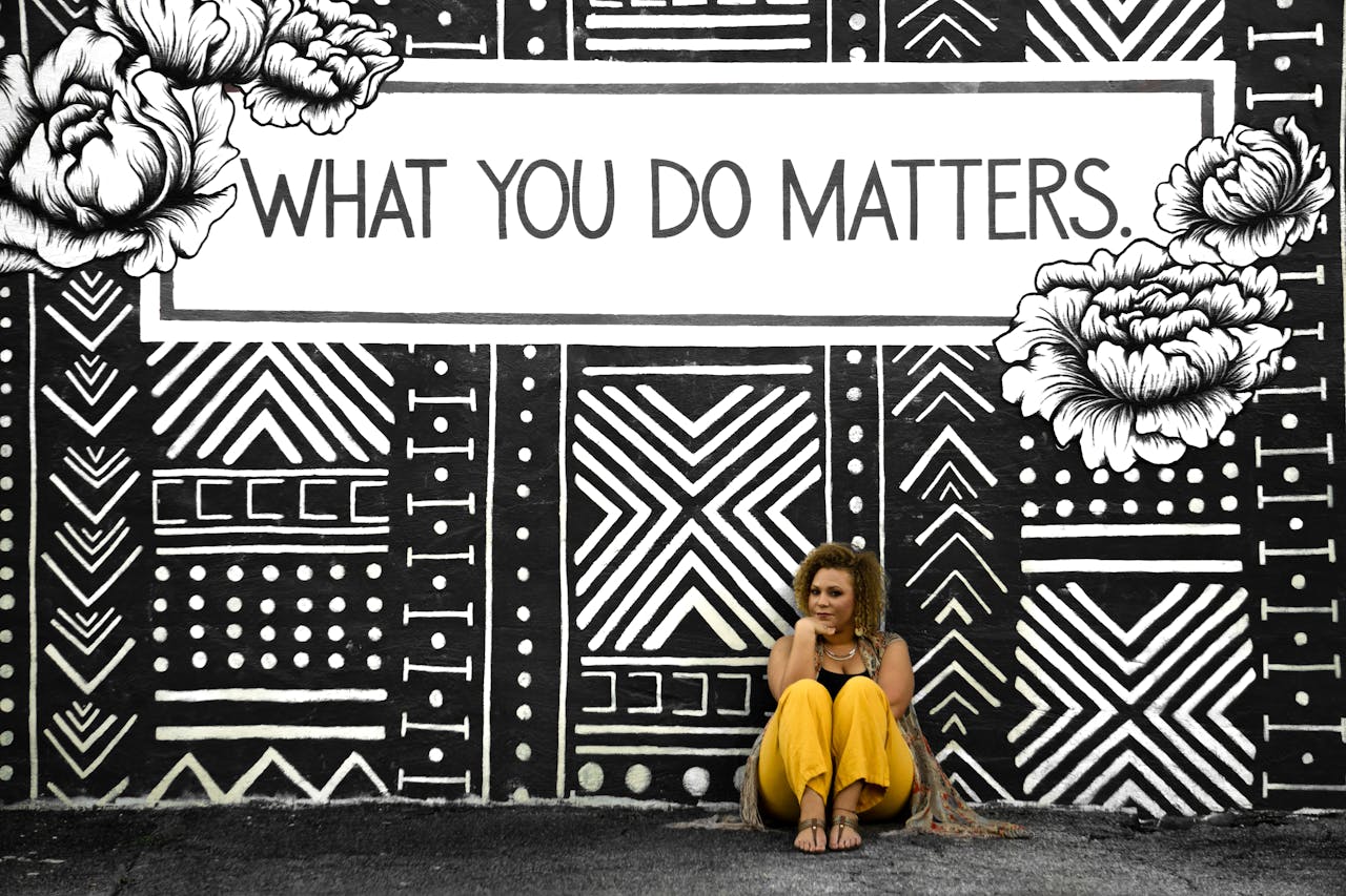 A woman sitting against a motivational mural reading 'What You Do Matters' in Birmingham, AL.